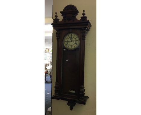 A walnut cased wall mounted clock with column design.
