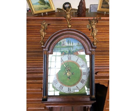 A wall mounted clock with handpainted river scene to face and topped with three figurines.