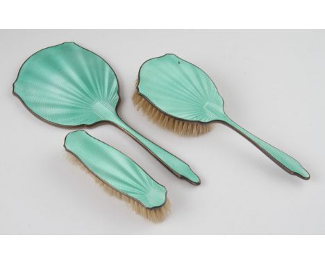 An Art Deco three piece silver green guilloche enamel dressing table set, comprising of a mirror, a hand brush and a hair bru