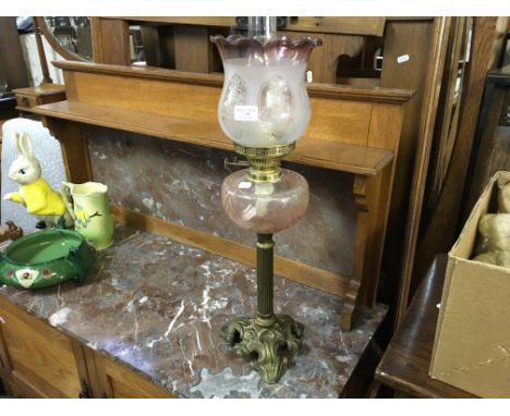 A brass oil lamp with glass vessel and etched shade.