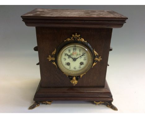 An oak cased mantel clock with French movement, brass fittings and feet.