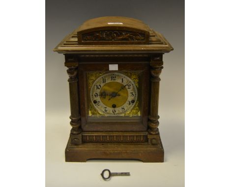 An early-20th century oak mantel clock, manufactured by Kinzle Schwenningen, Germany, the 15.5 cm brass and enamel dial with 