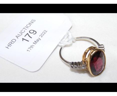 A gold ring set with facetted garnet and diamond shoulders