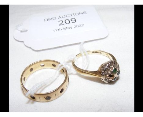 A gold wedding ring together with a gold ring set with emeralds