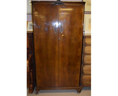 A mid 20th Century two door walnut veneered gentleman's wardrobe, the doors opening to reveal a shelf with sliding glass pane