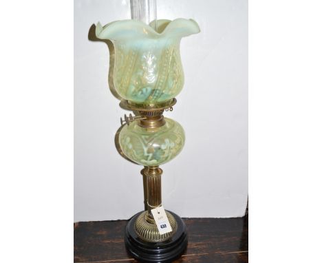 A Victorian brass oil lamp with vaseline glass shade and reservoir, raised on circular base.