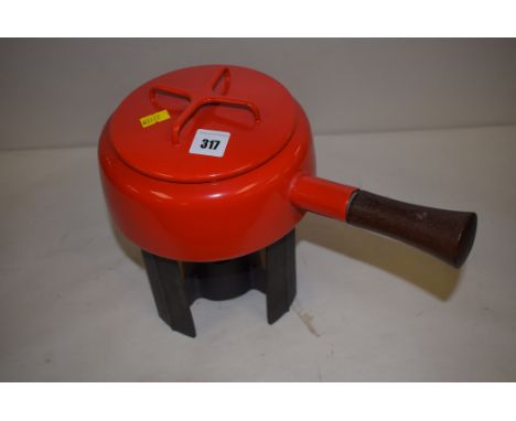 A Dansk red enamel saucepan with turned wooden handle, and cast metal stand.