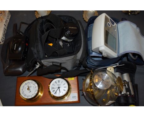 An Olympus OM-2N film camera; an Olympus XA3 compact camera; a pair of 10 x 25 binoculars; and a blood pressure machine; toge