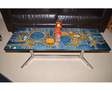 A pottery tiled and chromed metal coffee table, decorated in an abstract design, the tiles are probably by Poole Pottery, c.1