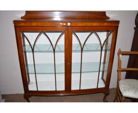 A 20th Century walnut veneered bowfront display cabinet with glaze panel doors, raised on cabriole legs terminating in claw a