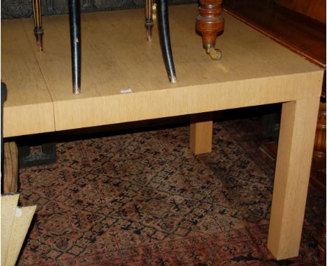 A contemporary light oak extending dining table, having pull-out action and two extra drop-in leaves