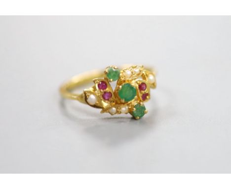 A modern yellow metal, emerald, ruby and seed pearl cluster set crossover ring, size L, gross weight 2.9 grams.