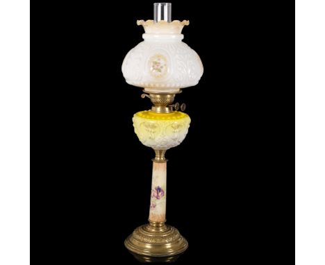 An Antique brass and glass oil lamp, with a white embossed and painted shade with yellow glass and gilded font, ceramic body 