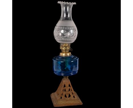 A Victorian glass and gilt-metal oil lamp, with etched shade and frilled edge, blue glass font on a pierced embossed metal ba