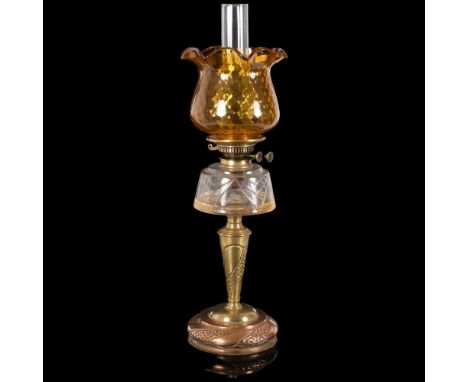 An Art Nouveau copper and brass oil lamp, with an amber frilled edge shade, and clear glass font, H65cmGood overall condition