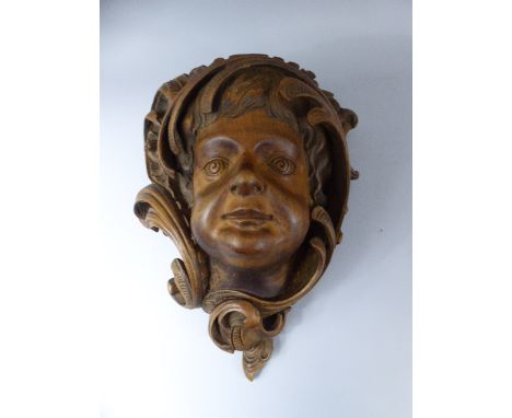 A 19th Century Black Forest Carved Lindenwood Wall Bracket Modelled as a Putti's Face Surrounded by Rococo Scrolls. 33x43cm