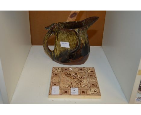 An old tile and an unusual pottery jug.