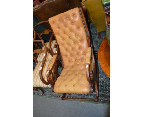 A brown button leather upholstered mahogany framed rocking chair.