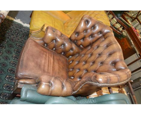 A Georgian style leather button upholstered and brass studded wing armchair.