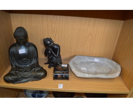 Two figures of Buddha, a stone trough and a cigarette box.