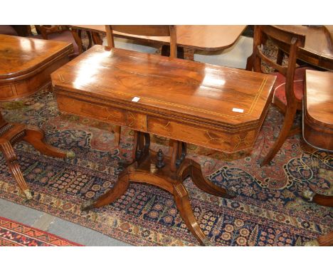 A Regency rosewood and brass inlaid foldover card table, the rectangular top with clipped corners on a twin lyre shaped suppo