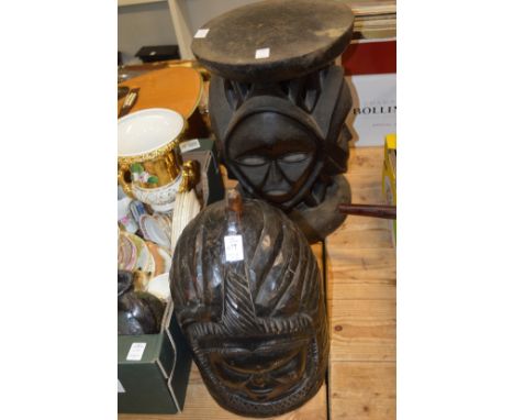 A large carved wood helmet mask and an African stool carved with masks.