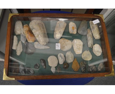 A mahogany display case containing a good collection of stone axes, flint spear and arrow heads etc.