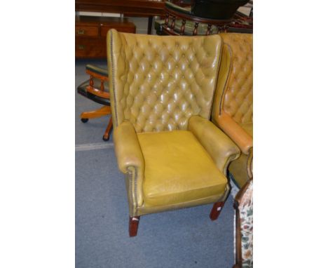 A Georgian style leather button upholstered and brass studded wing armchair.