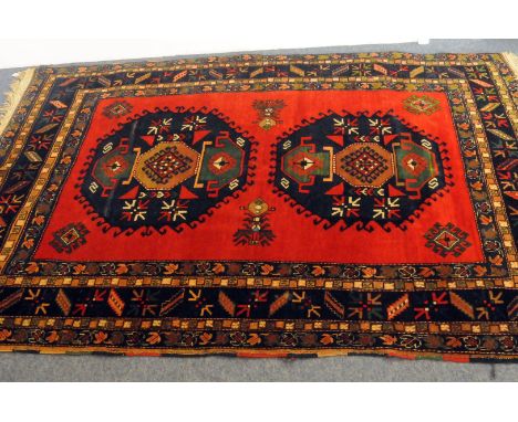 A 20th century Middle Eastern woollen carpet, possibly Caucasian, having bright red ground with two central medallions with m