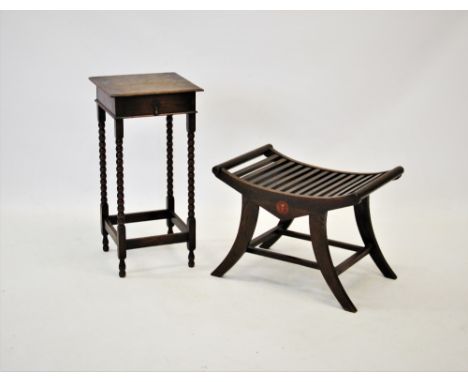 An early 20th century oak luggage stand with a concave slatted top raised upon sabre legs with plain cross stretchers, 59cm w