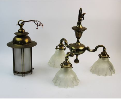 An early 20th century brass three branch ceiling light fitting, the three scrolling arms extending to reeded and frosted glas