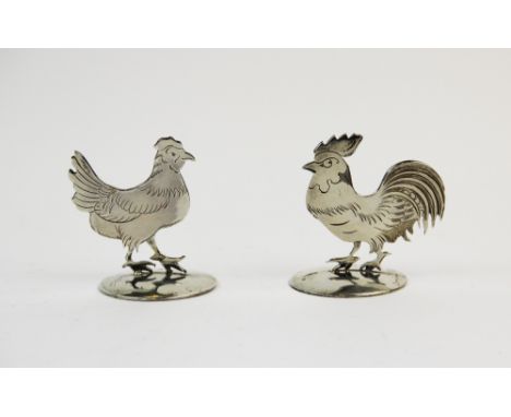 A pair of silver place card holders, Sampson Mordan & Co Ltd, Chester 1912, one designed as a Cockerel, the other example in 