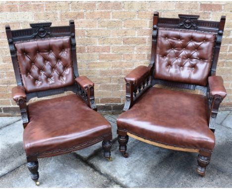 A PAIR OF VICTORIAN CARVED WALNUT FRAMED ARMCHAIRS  with button upholstered backs, on brass casters