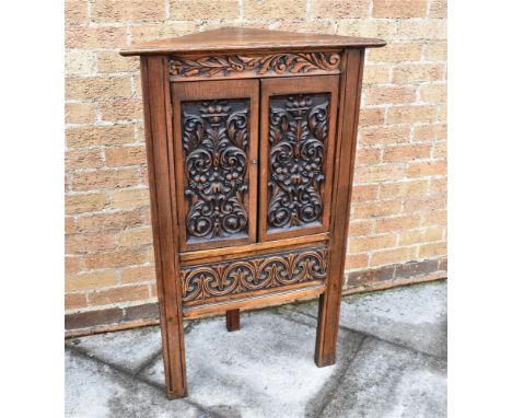 A CARVED OAK CORNER CUPBOARD  the doors opening to shaped shelf within, 69cm wide 111cm high