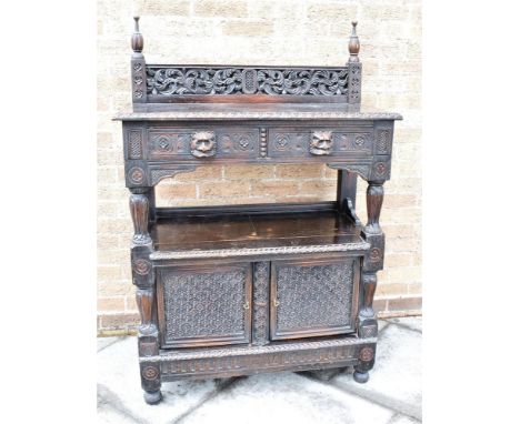 A CARVED OAK BUFFET  the top fitted with two drawers with lion mask handles, the base with pair of doors carved with repeatin