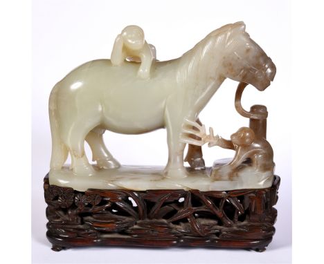 A CHINESE CARVED JADE FIGURE OF A HORSE standing tethered to a post, whilst a crouching monkey raises a three-pronged branch,