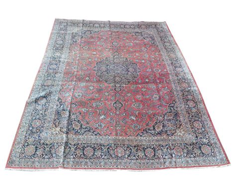 A Kashan carpet, the central floral rosette surrounded by floral scrolls on red ground, 442 x 322cms.