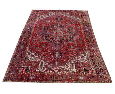 A Heriz carpet, of stylized floral design on a red ground, 361 x 264cms.