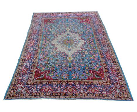 A Kirman carpet, the central rosette surrounded by floral scrolls and birds, on sky-blue ground, 440 x 298cms.