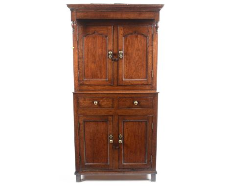 A Provincial oak cupboard, with 18th Century elements, the upper section with ogee cornice above a pair of turned baluster sp