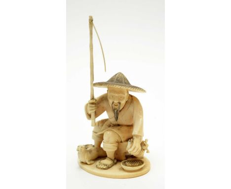 A Japanese carved ivory okimono of a fisherman, Meiji period, seated on a stool with broad straw hat, holding a bamboo rod an