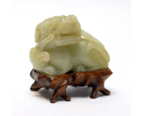 A Chinese carved Jade figure of a recumbent Buddhist lion, Qing, the stone on an even pale green colour with rust inclusion t