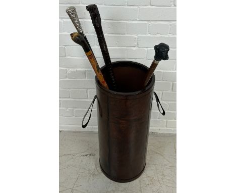 A TAN LEATHER STICK STAND ALONG WITH FOUR WALKING STICKS, To include one with horn handle amber finial.