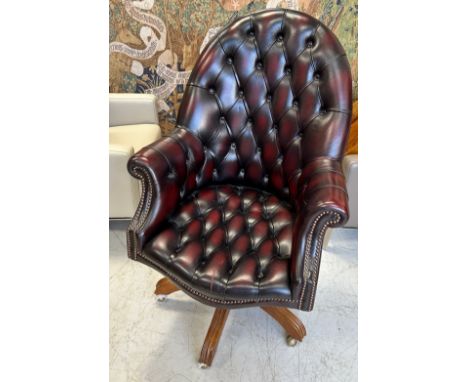 A REVOLVING CAPTAINS DESK CHAIR UPHOLSTERED IN BUTTON BACK CHESTERFIELD OX BLOOD LEATHER, 117cm x 70cm x 70cm