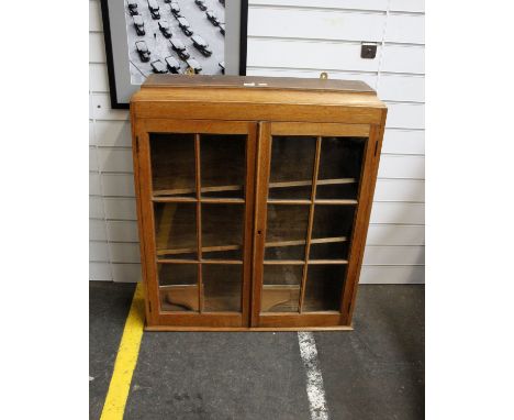 An early 20th century light oak hanging book case in the arts and crafts style. Glazed panel doors  65cm (H) 76cm (W) 19cm (D