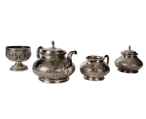 An Indian unmarked white metal three piece tea service, Teapot, jug and sugar with cast South Asian design, together with an 