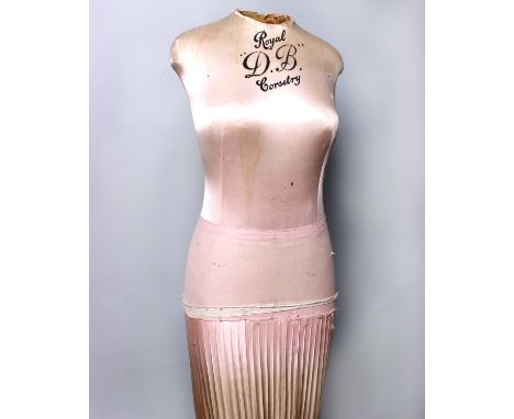 A 1930s Royal DB silk covered corsetry mannequin with a pink gathered silk skirt on a wooden stand