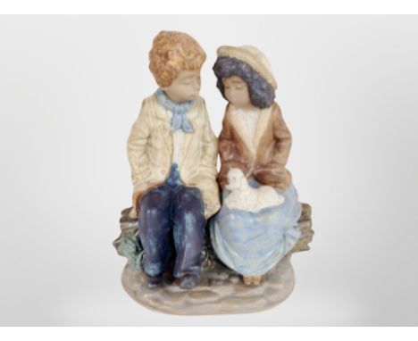 A Nao figure of a boy and girl sat on a tree trunk.