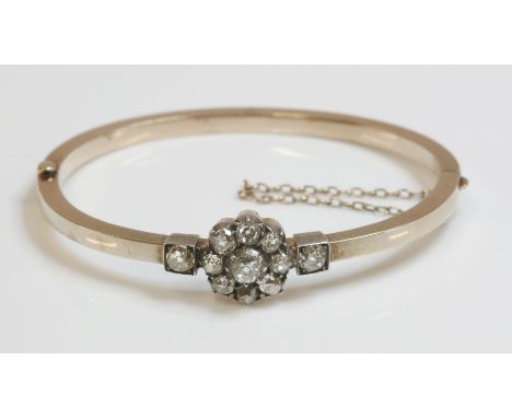 A late Victorian diamond set bangle, c.1900,with a circular cluster of nine old European cut diamonds in silver cut down coll