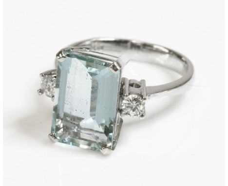 A white gold single stone aquamarine ring with diamond set shoulders,an emerald cut aquamarine, four claw set at the cut corn